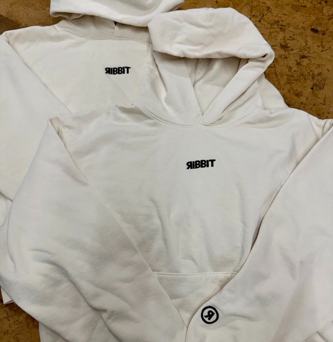 Two cream-colored Ribbit hoodies laid out, featuring the 'RIBBIT' text logo on the chest and a lightning bolt symbol on the pocket.