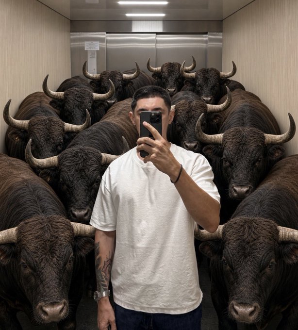 A man taking a mirror selfie in an elevator packed with numerous bulls/bovines surrounding him on all sides.
