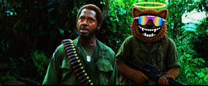 The image humorously combines a still of André 3000 and a character wearing a furry mascot mask from the movie "Four Lions," with no visible text or numbers in the image itself; the meme style ties into the post's playful $fuzzy community theme by suggesting a carefree, meme-inspired vibe that matches the crypto coin's branding.