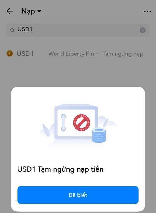 The image shows a phone screen with an app icon, which appears to be a banking app. The app has a red "no" symbol next to a lock and key icon, indicating that the user cannot access the app at this time. The text on the screen reads "USD1 Nguyên do là bầu phí WLFI đã các sàn HTX đóng băng một số địa chỉ ví on chain của số địa không nhưng giữa WLFI và stablecon". The app icon is located in the upper left corner of the screen, and the text is displayed at the bottom right corner.