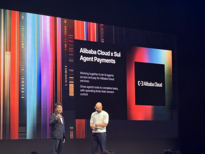 Two men presenting on stage in front of a large screen displaying 'Alibaba Cloud x Sui Agent Payments' with text about letting AI agents access and pay for Alibaba Cloud services.