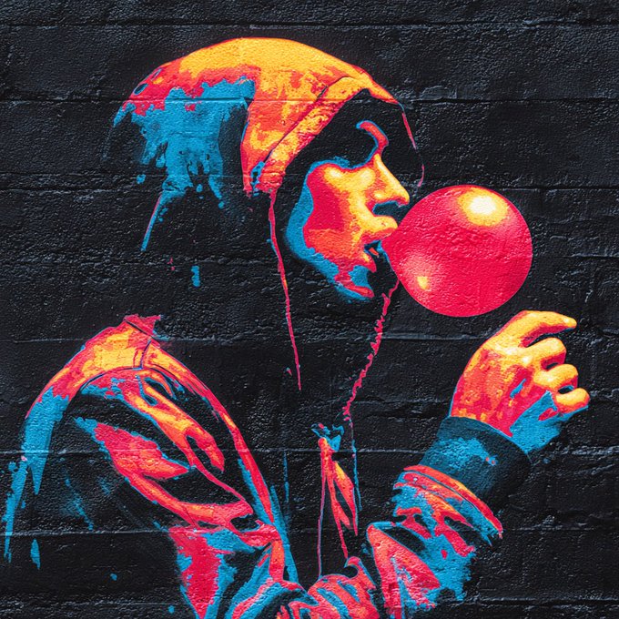 A vibrant street art mural on a brick wall depicts a hooded figure blowing a red bubblegum bubble in yellow, red, and blue tones.