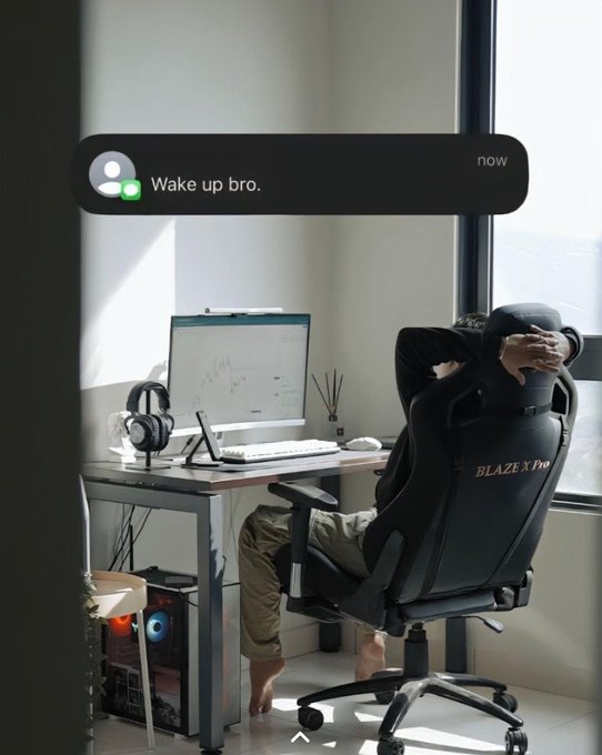The image shows a person sitting at a desk with a computer monitor, keyboard, mouse, and headphones. They are wearing a black chair that has "Blaze" written on it. The background of the image features a window overlooking an outdoor scene. There is also text in the image related to finance, technology, and AI.