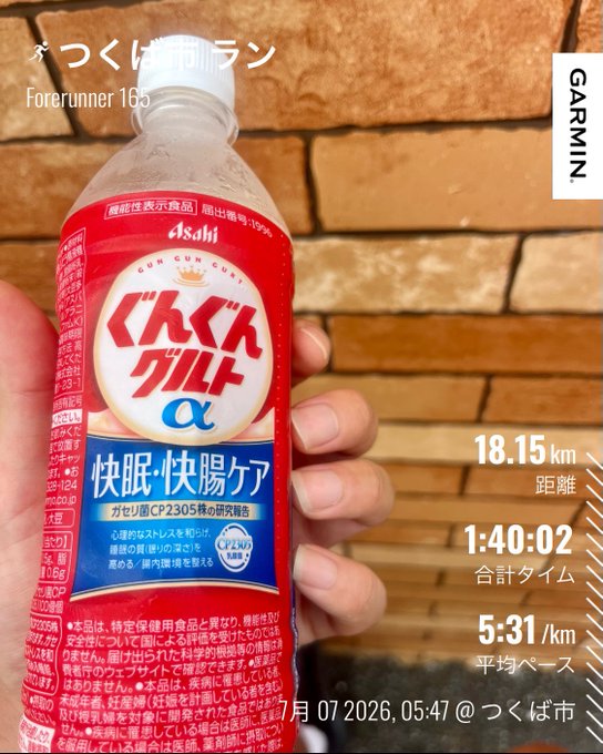 Garmin Forerunner 165 running summary titled 'つくば朝活ラン' showing 18.15 km distance, 1:40:02 total time, 5:31/km average pace, with a hand holding a bottle of 'ぐんぐんグルコα' in the foreground.