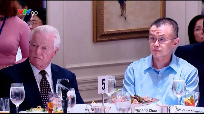 Two men sit at a formal dinner with name cards reading 'Mr. Robert Irwin' and 'Pengpeng Zhao', broadcast on a 'VTVgo' channel.
