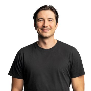 A stock photo-style portrait of a smiling man with dark hair wearing a black t-shirt against a white background.
