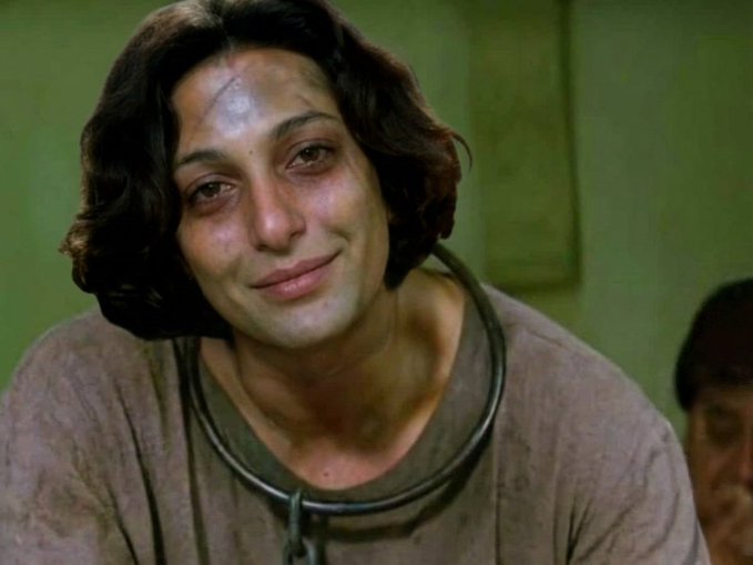 The image features an actor with a large nose, wearing a brown shirt that has a chain around their neck. The person appears to be smiling at the camera, possibly posing for a photo or participating in a photoshoot. The caption below the image reads "you make a post - no comment you buy ETH - it dumps you buy a meme - it rugs you long or short - get liquidated you farm an airdrop - ineligible you repost for giveaways - ineligible you gain 10 followers - 20 unfollows you speak on spaces - must follow host you give up".