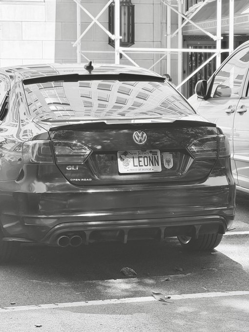 A black Volkswagen GLI with a New Jersey license plate reading "LEONN" is parked on a city street, supporting the claim that crypto influencer @cryptoleon has downgraded from a Porsche to a VW sedan.
