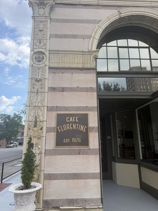 A sign reading "CAFE FLORENTINE EST. 1926" is mounted on the ornate facade of a historic stone building in Birmingham, Alabama, matching the post's description of admiring the city's architecture before the event began.