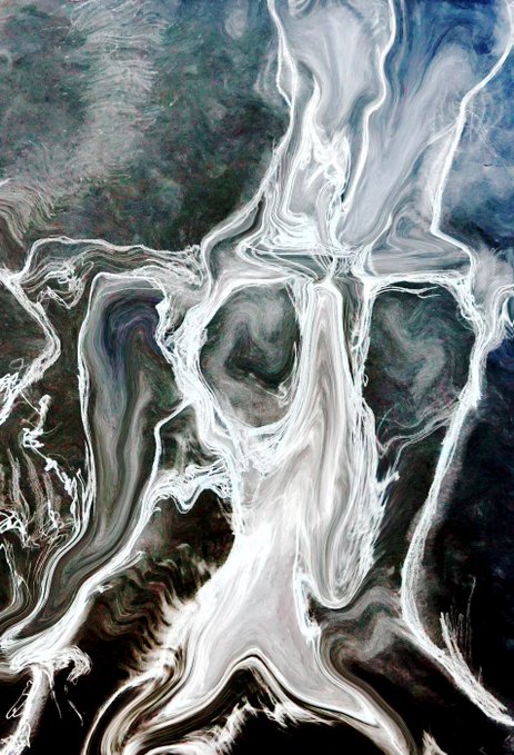 An abstract image resembling swirling white, gray, and dark earthy tones that suggest fluid movement or perhaps a spectral face hidden within the patterns.
