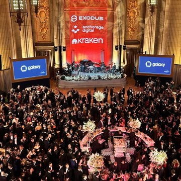 An aerial view shows a large formal gala event with many attendees seated at round tables in a grand hall; screens prominently display the logos for EXODUS, Anchorage Digital, Kraken, and Galaxy.