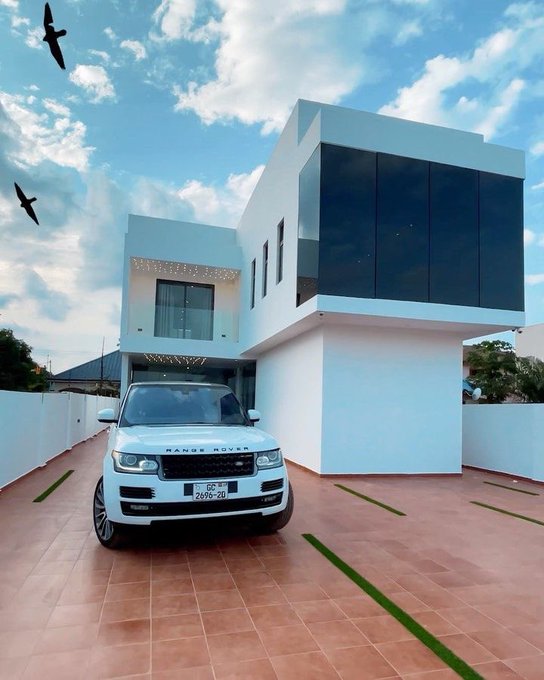 A white Range Rover (license plate "AGP-20") is parked in front of a modern two-story white house with large tinted glass windows under a partly cloudy sky, fitting the "gm" (good morning) Sunday post as a stylish start to the day.
