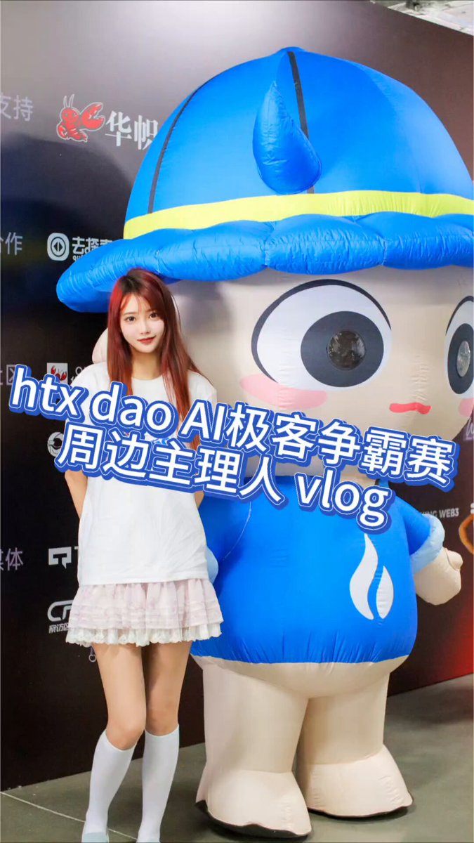 The image features a woman standing next to an inflatable blue character that resembles a cartoon character or mascot. The woman appears to be posing for a photo with the large inflatable figure, possibly at an event or promotional setting. The caption of the image reads "HTXDAO Peripherals Giveaway Results Announced! Thank you all for providing so many practical and awesome peripheral suggestions in the comments!".