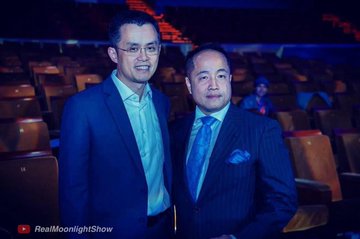 Two men pose for a photo in a theater setting, with the "RealloonightShow" logo visible in the bottom left corner. The image relates to the post by showing one of the individuals who allegedly posed with crypto figure Changpeng Zhao (CZ), discussed in the context of Harry Yeh (Ye Junde), a crypto mogul whose life ended dramatically after falling from a high-rise building.