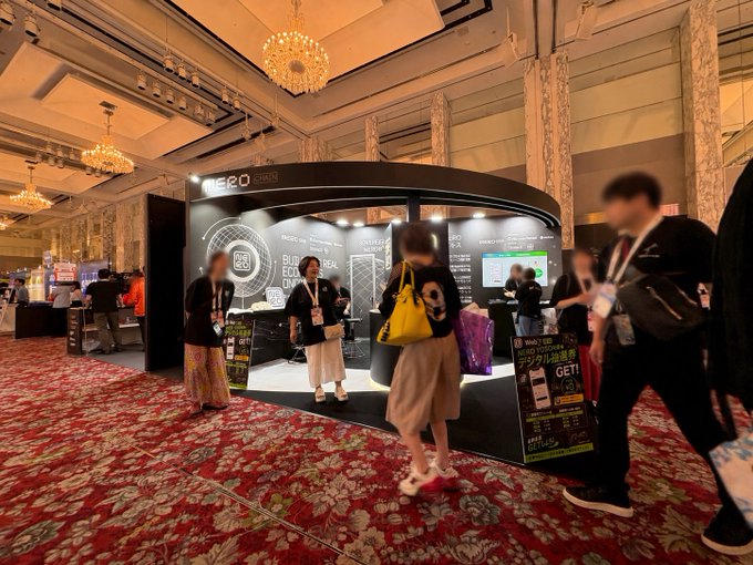 An exhibition booth for "NERO Chain" attracts attendees at a grand venue with chandeliers, where staff engage visitors with digital screens and promotional materials (including "GET! L7,380" signage), reflecting the post's enthusiasm about the lively two-day event and successful outreach efforts.