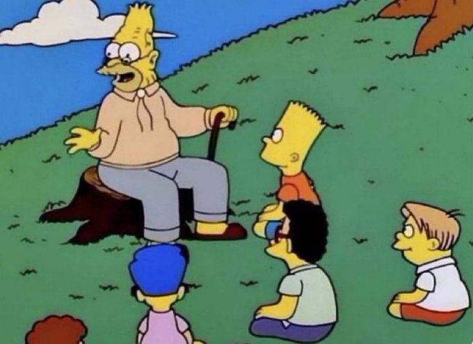 A scene from The Simpsons showing Grampa Simpson sitting on a tree stump holding a cane, surrounded by Bart, Milhouse, and other children on a grassy hill.