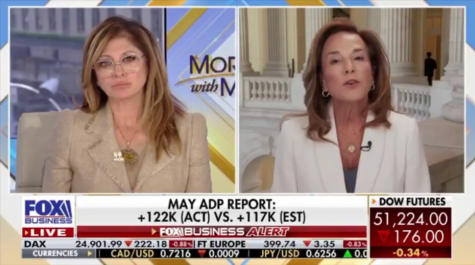The image shows a news broadcast with two women sitting across from each other, talking about a recent report or event. The news anchor is discussing the topic of Bitcoin clarity and its impact on the financial world. The background features a building, which could be an office or studio for the news organization. The text in the image includes phrases such as "Just In: US Rep. McClain" and "It's Here to Stay", indicating that this discussion is taking place within the context of current events and news coverage.