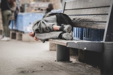 A person lies curled up on a wooden bench, clutching the edge as if clinging to the last bit of hope. The image humorously illustrates the post's sentiment of feeling defeated for missing out on the $TRUMP rally.