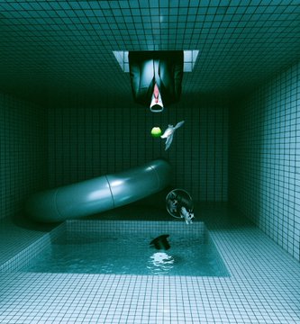 A surreal green-tiled room contains a pool, a person swimming underwater, an abstract metallic sculpture, and a figure hanging upside down from the ceiling.