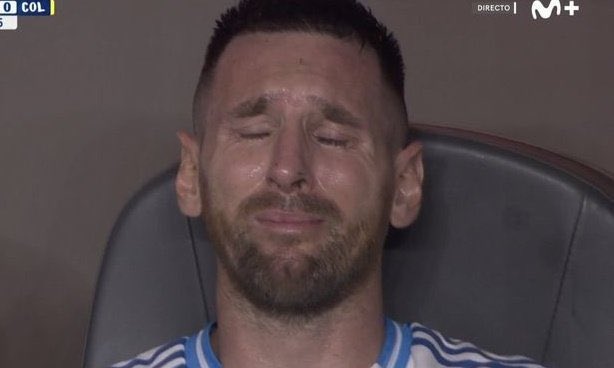 Lionel Messi sits on a bench with his eyes closed, appearing emotional and teary-eyed, with "M+" and "DIRECTO" broadcast logos in the corner.