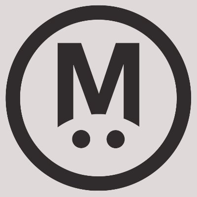 The image shows a circular black logo with a bold letter "M" above two dots, which appears to be the MegaETH project logo referenced in the post. The caption would read: "The MegaETH (@megaeth) logo is displayed as a circular black icon featuring a bold 'M' with two dots beneath it, representing the project mentioned in the post."