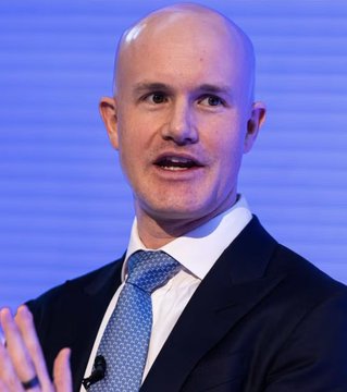 A bald man in a dark suit, white shirt, and blue patterned tie speaks while gesturing with his hand against a blue background, identified by the accompanying post as Coinbase CEO Brian Armstrong making bullish remarks that Bitcoin has already bottomed and will trend higher.