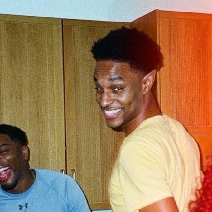 The image shows two young men laughing and smiling warmly in a casual indoor setting, with one in a yellow shirt beaming at the camera while the other in a gray Under Armour shirt laughs in the background. The post celebrates a crypto influencer named $ANSEM for airdropping $7M to token holders, suggesting the image captures the joyful, behind-the-scenes camaraderie of meme coin culture that this post glorifies.