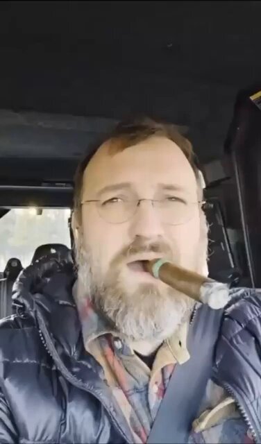 The image features a man wearing glasses, a beard, and a jacket with a hood, who appears to be driving a car while holding a cigar in his mouth. The caption of the image reads "Only top 100 coin not effected by Mythos release is $ADA because nothing has even been built on that chain". This suggests that there might have been an issue with the Mythos release affecting only a specific coin, and it is not applicable to all coins.

The man's driving behavior indicates that he may be in a hurry or simply enjoying his cigar while traveling. The image does not provide any additional information about the car model or license plate number.