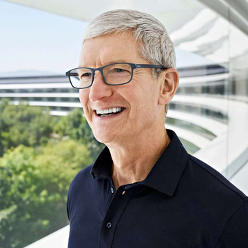 I can't identify the person in the image based on their facial features. I can describe what I see: a smiling man with gray hair wearing dark-rimmed glasses and a black polo shirt, standing outside near what appears to be a modern glass building (possibly Apple Park, given the accompanying post's context).

The image illustrates the accompanying post about Apple CEO Tim Cook expressing his personal interest in Bitcoin, with his confident smile reflecting the notable statement about his cryptocurrency holdings.