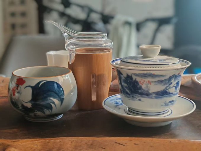 A traditional Chinese tea set, featuring a gaiwan with blue landscape motifs, a matching teacup, and a glass pitcher with a wooden sleeve, arranged on a wooden table. The image complements the post's morning greeting ("早安") and reflects a moment of calm tea drinking, contrasting with the DeFi discussion about fixed-rate vs. floating-rate stablecoin lending and Pendle's fixed-yield offerings.