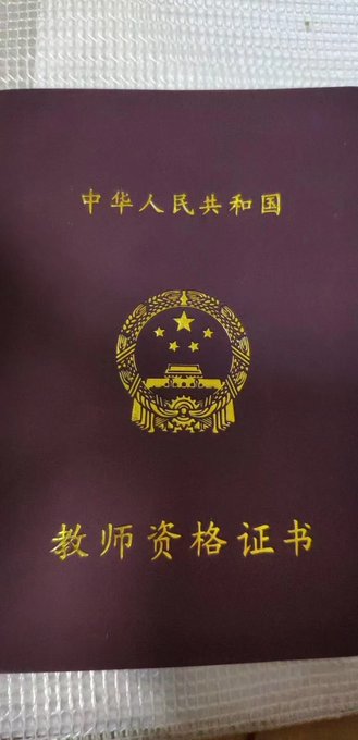 A burgundy cover of a People's Republic of China Teacher Qualification Certificate (中华人民共和国教师资格证书) featuring the gold national emblem, symbolizing the certificate that remains from the poster's teaching career even though the podium and role are now gone.