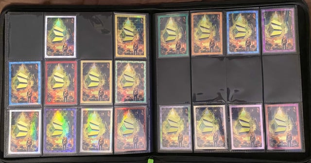 The image shows a black binder with multiple pockets, open to reveal an assortment of cards inside. There are at least 13 cards visible, each featuring different designs and colors. The cards appear to be related to tarot or fortune-telling, as they come in various shapes and sizes. The binder is placed on a table, and the cards are neatly organized within it.