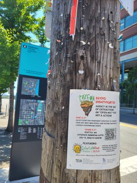 A wooden utility pole on a sidewalk displaying flyers, including one for 'JULIASO BRIDG Kwantikarto' featuring what appears to be a sunflower and event details.