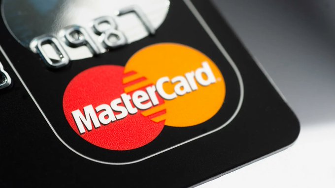A macro close-up photograph of a black credit card displaying the raised, embossed red and yellow interlocking circles of the MasterCard logo.