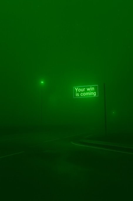 A glowing green street sign in a foggy night reads "Your win is coming," paired with the post's message "Claim it." as an optimistic invitation to seize the promised victory.