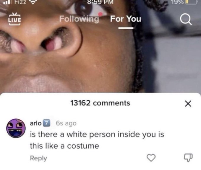 A TikTok LIVE screenshot showing a close-up of a person's face with the comments panel open, displaying a comment from user 'arlo' asking 'is there a white person inside you is this like a costume' among 13162 comments.