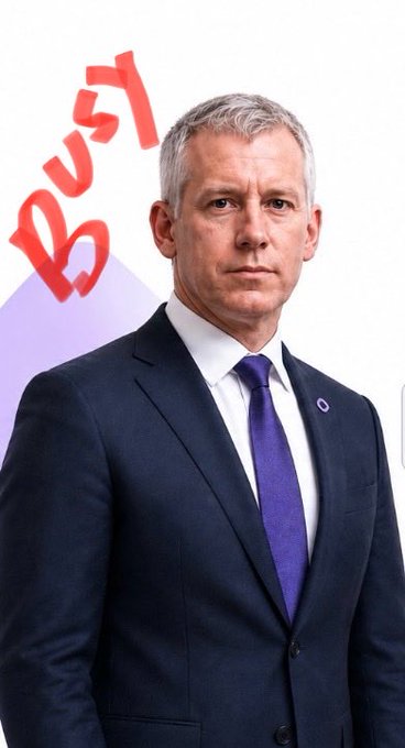 A man in a dark suit and purple tie poses in front of a backdrop with the red 'BTV' logo.