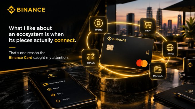A Binance promotional advertisement showing a black Binance Mastercard with floating icons for Spend, Shop, Trade, Manage, and Travel, alongside the tagline 'What I like about an ecosystem is when its pieces actually connect.'