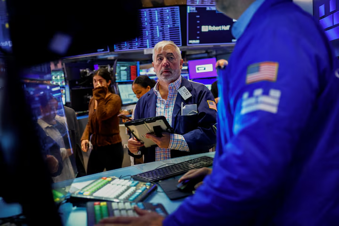 Traders on a busy stock exchange floor, with one man in a blue jacket holding a tablet while another works at a monitor displaying the Robert Half ticker.