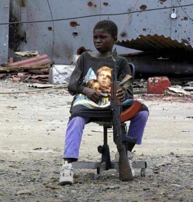 A child sits solemnly in an office chair holding a large rifle amid debris, juxtaposed with the meme about Mexc watching over-leveraged traders—drawing a darkly humorous parallel between an innocent child armed for war and the crypto exchange "watching" reckless traders face the consequences of their high-risk positions.