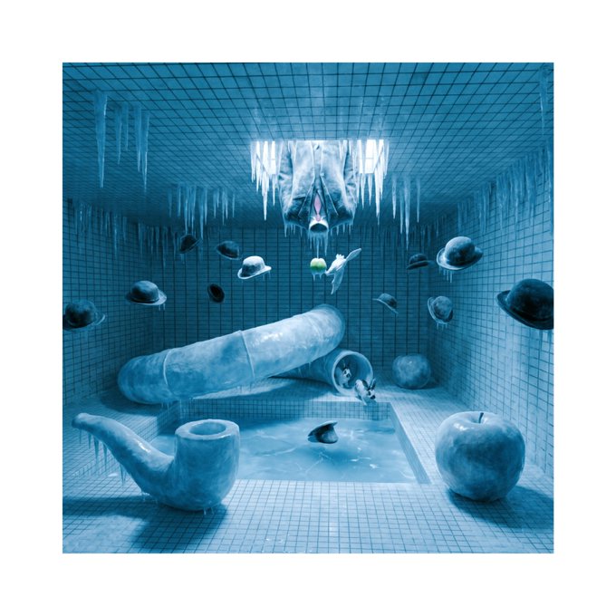 A surreal blue-tiled room features floating objects including planets, a pipe, an apple, an inverted face on the ceiling with hanging icicles, and a tiled pool.