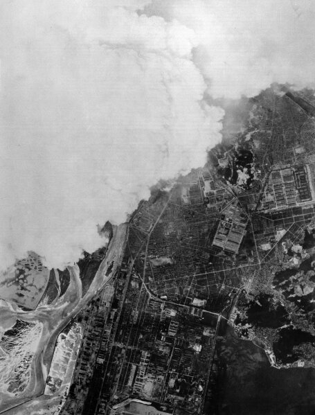 This black-and-white aerial photograph appears to depict a large-scale industrial disaster or wildfire, with a massive plume of smoke billowing across a coastal cityscape. The image likely serves as a metaphorical representation of the dramatic price volatility or "burning" market conditions referenced in the accompanying post about XRP's performance during week 29.

No visible text, numbers, or tickers can be discerned in the image itself.