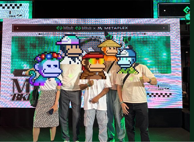 Four people pose in front of a green screen displaying 'bitkub x METAPLEX' logos, with pixelated NFT monkey avatars digitally placed over their faces.