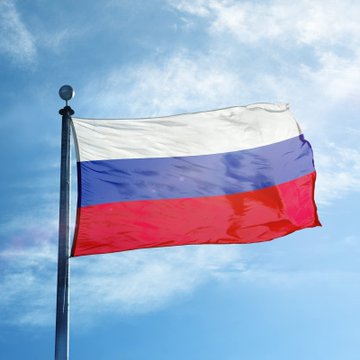 A Russian tricolor flag waves against a partly cloudy blue sky, symbolizing the country's legislative efforts as lawmakers prepare to advance a major cryptocurrency regulation bill aimed at defining digital asset rules and combating fraud.