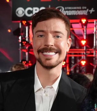 A smiling man in a black suit and white shirt poses at an event with a "CBS" and "Paramount+" branded backdrop behind him. The image appears to relate to a social media post promoting a cryptocurrency called "$BEAST," purportedly endorsed by the creator MrBeast, though the man pictured is not identifiable as MrBeast.