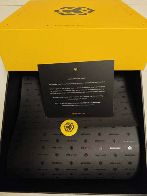 The image shows a black box with yellow writing, which appears to be an advertisement or a message related to Bitcoin. The box has a note attached to it that reads "Welcome to Bitcoin". This suggests that the box might contain information about Bitcoin or possibly promote its use in some way.