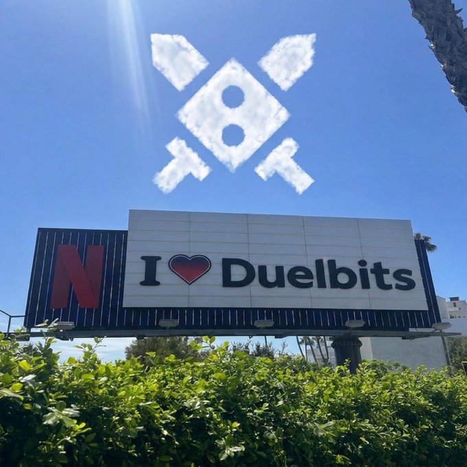 A billboard featuring the Netflix logo and the text "I ❤️ Duelbits" stands beneath a sky decorated with a cloud formation shaped like the Duelbits emblem. The image showcases a clear promotional tie-in between Duelbits and Netflix, aligning with the post's theme of running a giveaway for SOL wallets.