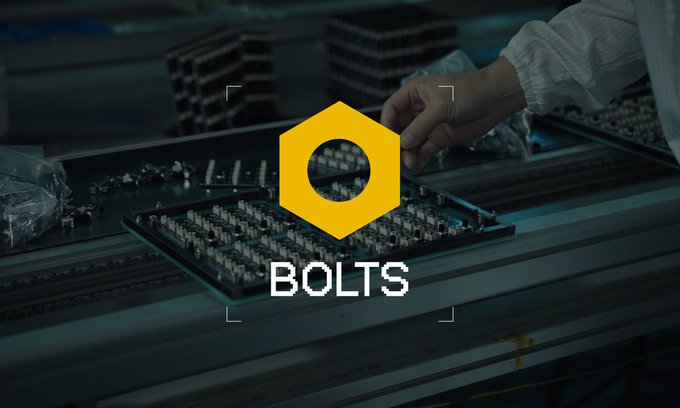 A logo for 'BOLTS' featuring a yellow hexagonal nut icon overlaid on a dark, blurred background of a manufacturing workspace.