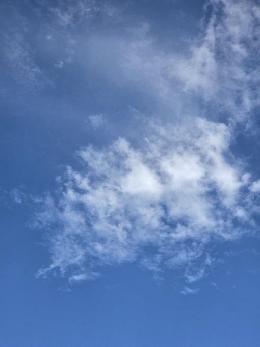 A bright blue sky filled with wispy white cirrus clouds and a larger cloud formation near the center.
