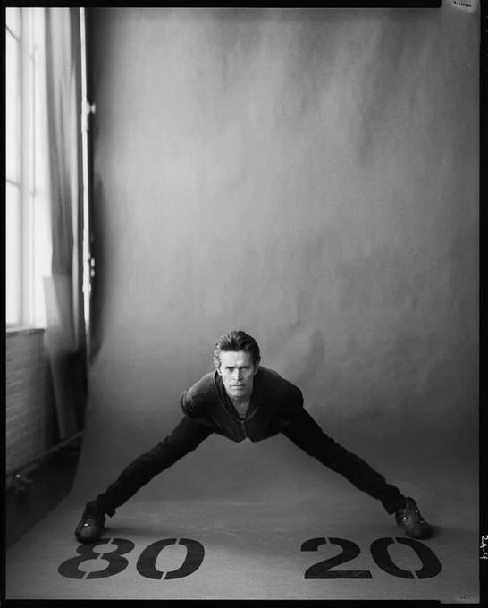 A man in a wide stance straddles the numbers "30" and "20" on the floor of a black-and-white photo studio, visually emphasizing the shift from a 30/70 to an 80/20 split that aligns with the announced contract upgrade changes.